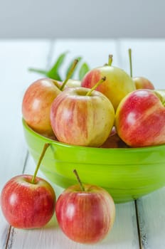 fresh red and yellow apple with green bowl on wooden background