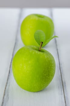 Ripe green apple with leaf  on a wooden background