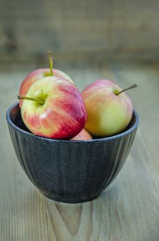 Red and yellow apple with black bowl , organic fresh fruit on wooden background