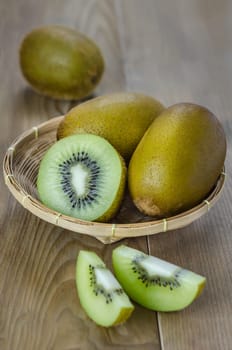 kiwi fruit and sliced with bamboo basket on wooden background