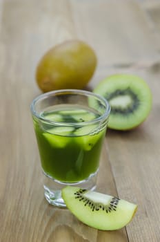 glass of kiwi juice with fresh fruits on wooden table