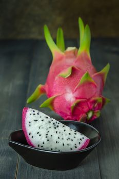 Ripe Dragon fruit  with slice in bowl over wooden background , still life