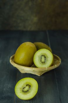 kiwi fruit and sliced with bamboo basket on wooden background , still life