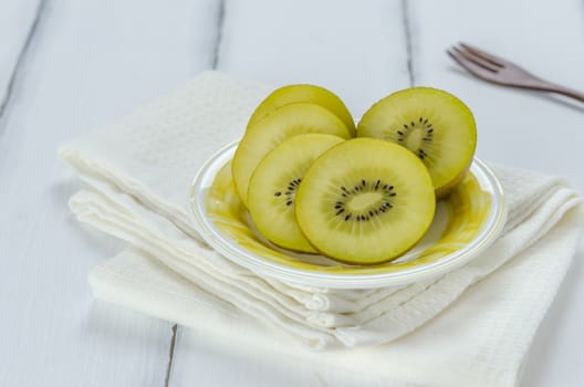 golden kiwi fruit and sliced on dish over white wooden background