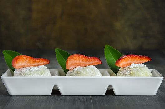 Strawberry Daifuku Mochi Japanese dessert on white plate over wooden background, still life