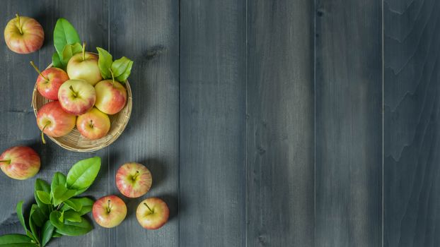 Top view red and yellow apple with leaves and  bamboo basket on wooden background with free space for text