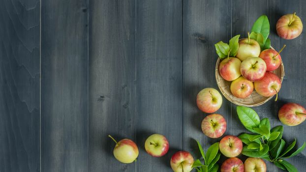 Top view red and yellow apple with leaves and  bamboo basket on wooden background with free space for text