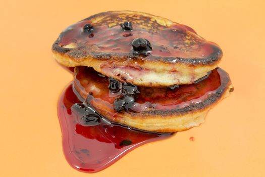 Closeup delicious puffy pancakes with jam on a yellow background