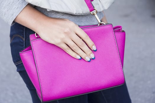 Hand girl with fashionable stylish handbag on a pink manicure