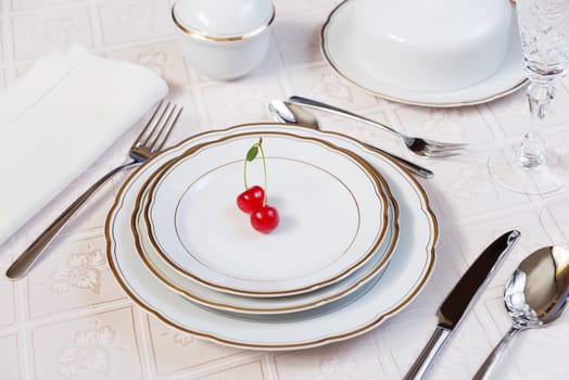 Beautifully decorated table with white plates, crystal glasses, linen napkin, cutlery and tulip flowers on luxurious tablecloths