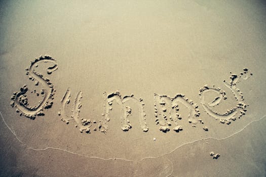 Summer text written on the sand on beach vintage style