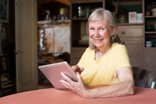 Happy female adult woman holding tablet computer at table indoors