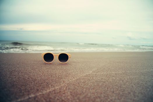 Sunglasses on the sand on beach beautiful summer photo in vintage style