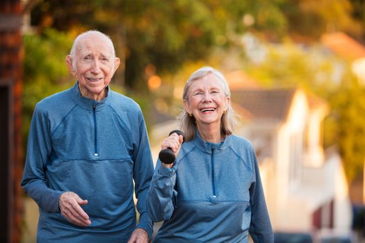 Happy senior couple in matching blue athletic outfits together outside