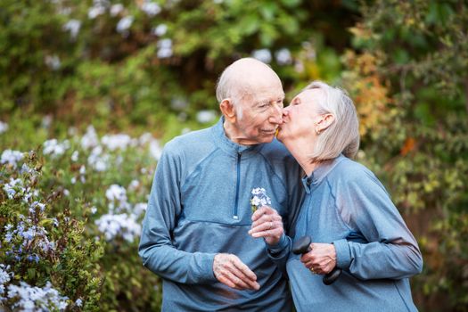 Loving senior couple kissing each other outside in front of garden