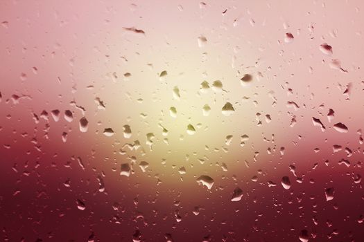 Rain water drops on glass window. Beautiful background of rain drops on glass at the sunset