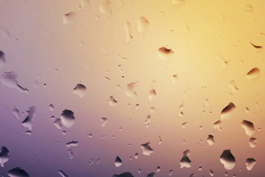 Rain water drops on glass window. Beautiful background of rain drops on glass at the sunset