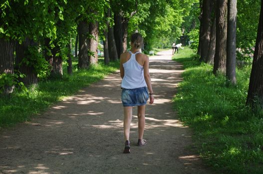 young woman on the walkway in the park Aleksandriya in Peterhof, Saint Petersburg, Russia