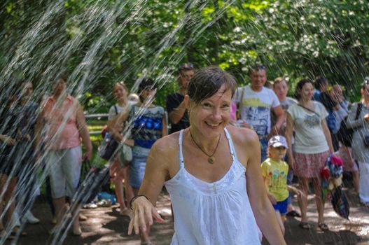 happy young woman gets wet by Fontaine in the Grand Peterhof Palace and The Grand Cascade and Samson Fountain in Russia