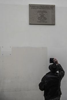 FRANCE, Paris : A man takes pictures of a memorial plaque bearing the names of the victims of the Charlie Hebdo attack on January 7, 2015 in Paris on January 5, 2016. The name of cartoonist Wolinski was misspelled Wolinsky and Paris city hall said on January 5, 2016 it will be fixed within an hour.