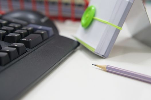 Black computer and office supplies on white table at workplace.