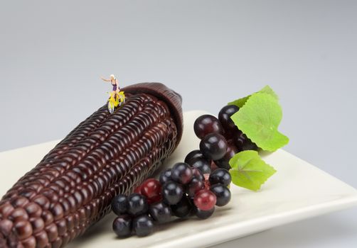 Miniature women exercises by bicycling on black corn in morning.