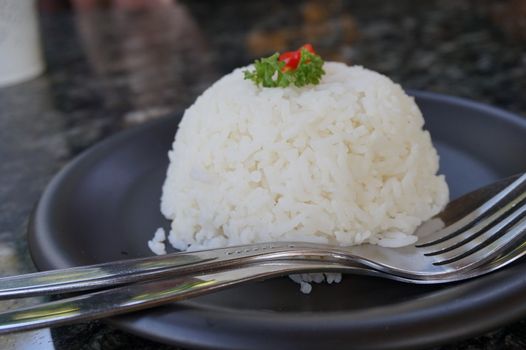 cooked rice with a spoon and fork on black plate