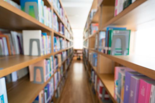 Blurred background of public library, bookshelf with books, diminishing perspective