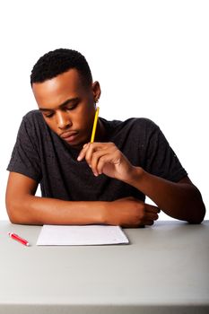 Handsome student thinking concentrating focussing for test examination sitting at desk, on white.