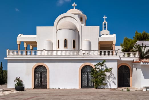 View of the Orthodox church with white walls in the Greek village of Anavisos in the summer sunny day.
