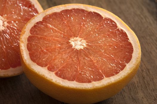 Fresh half pink or rose grapefruit in a close up view on a wooden table showing the juicy tangy pulp and segments