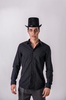 Portrait of a Young Vampire Man with High Hat and Black T-Shirt, Looking at the Camera, On Light Background.
