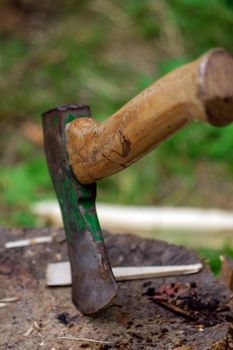 a Ax in the deck on a background of green grass and firewood