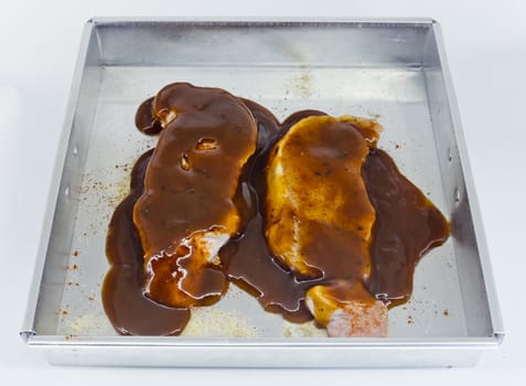 Raw pork fillet with barbecue sauce in baking tin