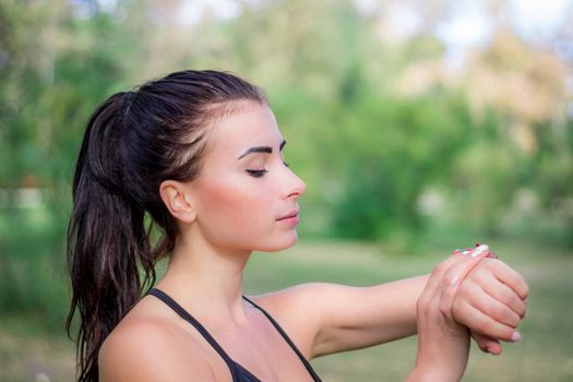Young fitness girl checks stopwatch tracker on her wrist during running outdoor