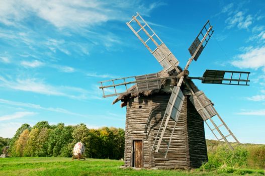 Old wooden windmill in the background of the autumn forest