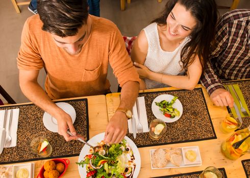 Happy couple at the restaurant and being served of food in the plate