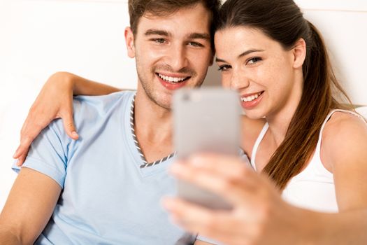 Young couple on bed making selfies with a phone