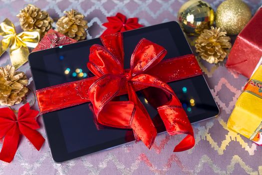 Tablet pc for Christmas with gifts, decorations on table.
