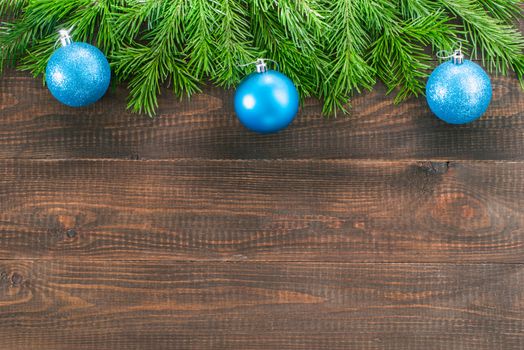 Christmas fir tree with decoration on dark wooden board background. Border art design with Christmas tree and blue baubles. Xmas and new year concept with copy space