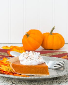 Slice of fresh pumpkin pie with whipped cream.