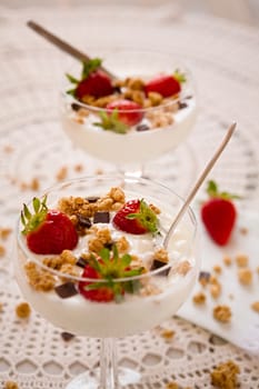 Dessert with strawberries cereals and chocolate flakes inside a cup with plain yogurt