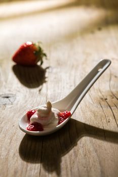 Mascarpone cream and strawberries in backlight over a wooden background