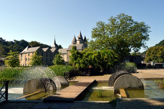 Waterfalls and fountains of cylindrical shape with a castle in the background.