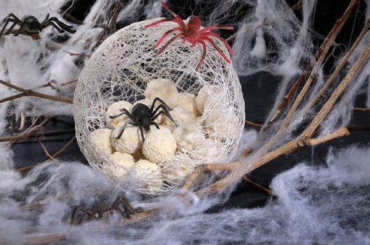 candy in the form of spider eggs in a cocoon with a spider on the table for Halloween