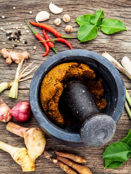 Assortment of Thai food Cooking ingredients and Paste of thai popular food red curry  with mortar and pestle on rustic wooden background. Spices ingredients chilli ,pepper, garlic,galanga lemongrass and Kaffir lime leaves .