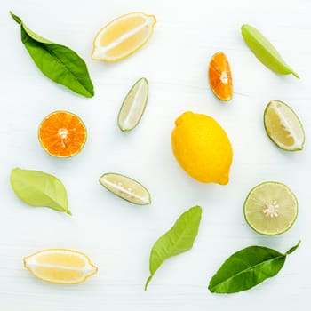 Mixed fresh citrus fruits and leaves background. Fresh lemons, lemon slice ,lime and orange on white wooden table with flat lay.