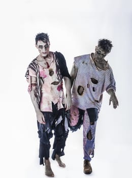 Two male zombies standing on black background walking towards camera