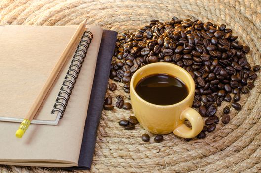 Cup of coffee with  notebook on a jute rope.