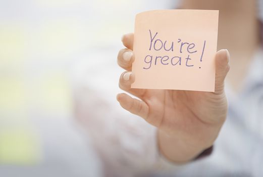 Woman holding sticky note with You are great text